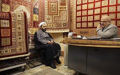 An Iranian merchant talks on a mobile phone at his shop in the carpet market of Tehran's old main bazaar. (photo credit: c/o AP)