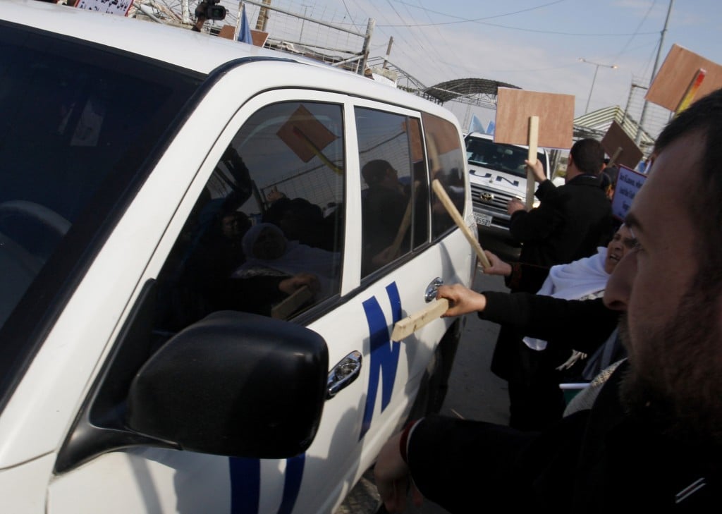 Palestinian demonstrators use sticks to hit one of the vehicles in the convoy of U.N. Secretary-General Ban Ki-moon as it enters the Erez border crossing between Israel and Gaza (photo credit: AP/Hatem Moussa)