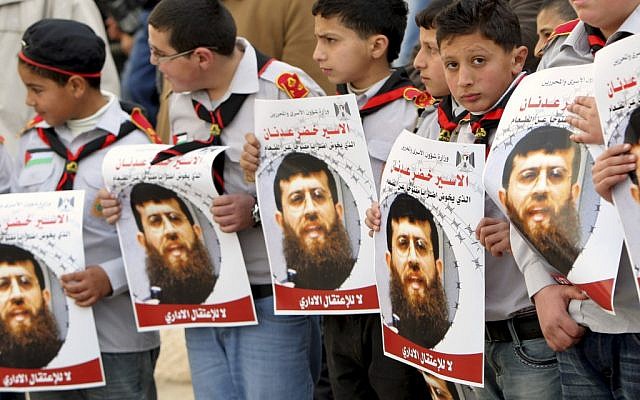 Palestinian schoolboys hold images of Khader Adnan, in the West Bank city of Jenin last week. (photo credit: AP/Mohammed Ballas)