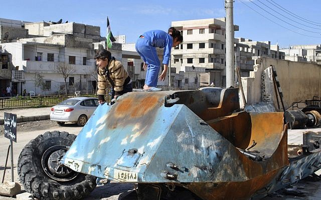Syrian girls play on top of a destroyed Syrian riot police tank in the Bayada neighborhood in Homs province, Syria. The EU expanded its financial sanctions against the Assad regime on Monday 27th February 2012 to try and bring an end to the violence. (photo credit: AP)