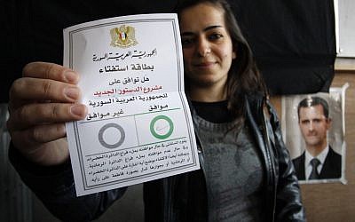 A Syrian woman shows her ballot paper at a polling station during a referendum on the new constitution in Damascus on Sunday (photo credit: AP/Muzaffar Salman)