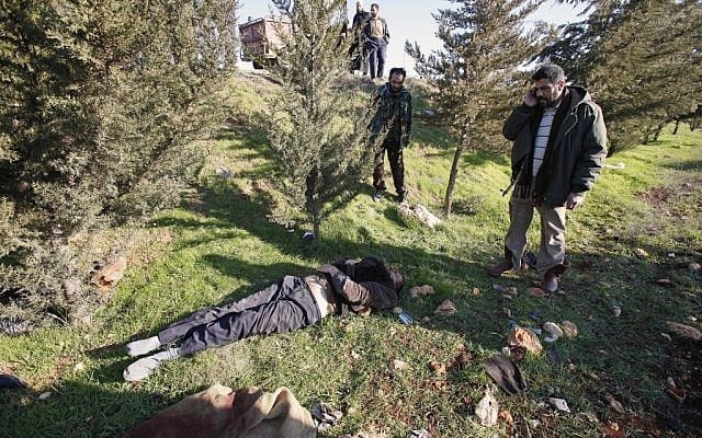 Syrians stand near the body of a man local residents say was an activist who was tortured to death by the Syrian government and dumped by the side of the road in Idlib, northern Syria, yesterday (Photo credit: AP) Syrians stand near the body of a man local residents say was an activist who was tortured to death by the Syrian government and dumped by the side of the road in Idlib, northern Syria, yesterday (Photo credit: AP)