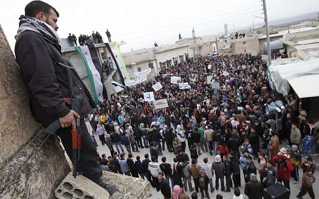 A member of the Free Syrian Army stands guard as anti-Syrian regime protesters hold a demonstration in Idlib, Syria, Monday(Photo credit: AP) A member of the Free Syrian Army stands guard as anti-Syrian regime protesters hold a demonstration in Idlib, Syria, Monday(Photo credit: AP)