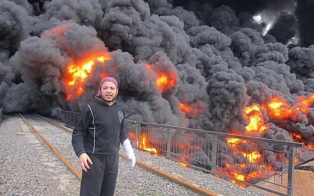 An anti-Syrian regime activist stands in front of flames and black smoke from a bombed oil pipeline in Homs, Syria in February 2012 (photo credit: AP Photo/Local Coordination Committees in Syria) An anti-Syrian regime activist stands in front of flames and black smoke from a bombed oil pipeline in Homs, Syria in February 2012 (photo credit: AP Photo/Local Coordination Committees in Syria)