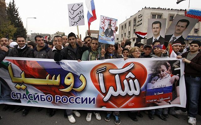 Pro-Syrian regime protesters hold a banner in Arabic that reads, 'Thanks Russia,' as they cheer a convoy believed to be transporting Russian Foreign Minister Sergey Lavrov in Damascus, February 7 (photo credit: AP/Muzaffar Salman)
