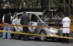 Indian officials examine a car belonging to the Israeli embassy, after Monday's attack wounded one person. (photo credit: AP Photo/Mustafa Quraishi)