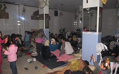 In this undated citizen journalism image accessed on Thursday, Syrian families gather at a shelter hiding from Syrian government forces shelling, in the Baba Amr neighborhood of Homs province. (photo credit: AP Photo/Local Coordination Committees in Syria)