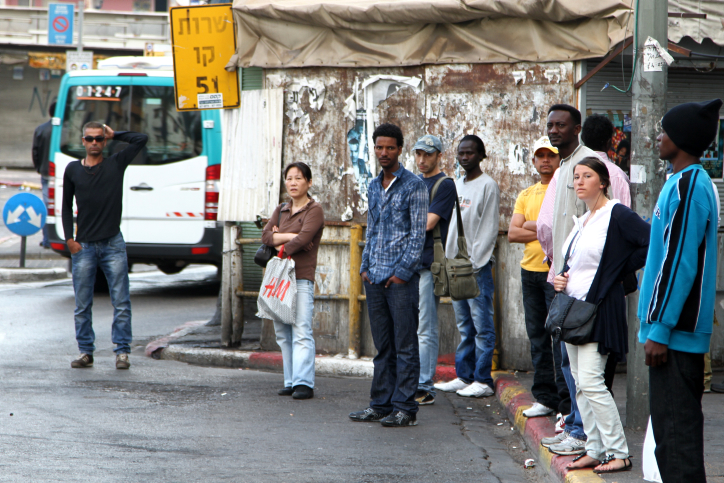 Many migrant workers, like these at a bus stop in South Tel Aviv, and their families could be deported in the coming month. (photo credit: Nicky Kelvin/Flash90).