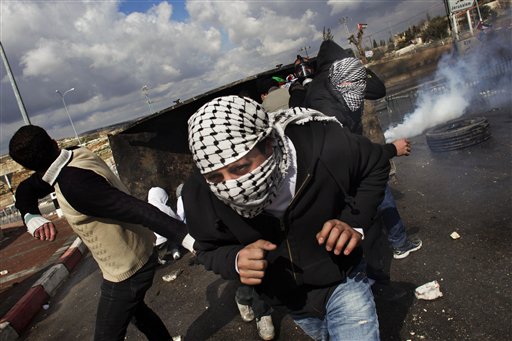 Masked Palestinian stone-throwers run away from tear gas fired by Israeli security forces, not pictured, during clashes in Al-Ram, near Jerusalem, Saturday. The clashes erupted after the funeral of a Palestinian who was shot dead while throwing fire crackers at troops on Friday. (photo credit: AP photo/Bernat Armangue)
