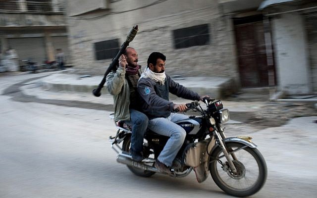 Syrian rebels ride through Kafar Taharim on Friday, while the bombardment of Homs by Assad forces continued. (photo credit: AP/Rodrigo Abd)