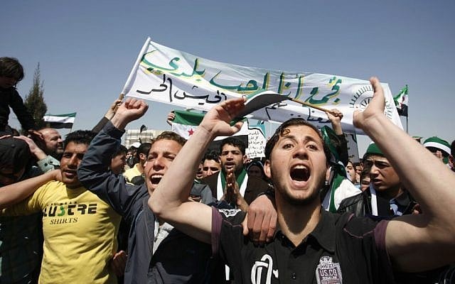 Syrians chant anti-Assad slogans in front of the Syrian embassy during a protest in Amman, Jordan, on Friday. The Arabic banner reads, "I love my country and the Free Syrian Army." (photo credit: AP Photo/Mohammad Hannon)