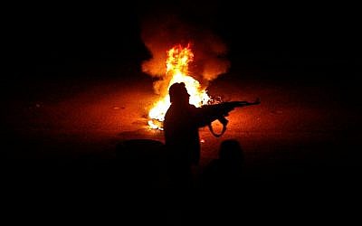 A Syrian rebel fires at a Syrian army checkpoint in a suburb of Damascus (photo credit: AP)