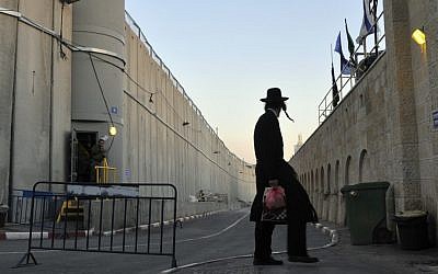 A man walks past the security barrier near Rachel's Tomb, on the outskirts of Bethlehem  (photo credit: Serge Attal/Flash90/File)