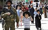 Soldiers guard Purim celebrants in the West Bank city of Hebron on Thursday. (photo credit: Miriam Alster/Flash90)