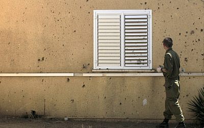 An Israeli soldier examines a house hit by a mortar shell in March (photo credit: Tsafrir Abayov/Flash90)