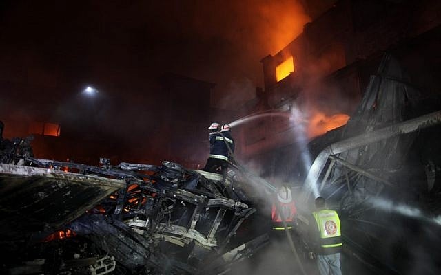 Palestinian fire fighters try to extinguish a blaze at a burning factory after an Israeli missile strike in the east of the Gaza Strip early on Wednesday. (photo credit: Wissam Nassar/Flash90 Palestinian fire fighters try to extinguish a blaze at a burning factory after an Israeli missile strike in the east of the Gaza Strip early on Wednesday. (photo credit: Wissam Nassar/Flash90