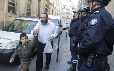 Illustrative photo: A schoolchild and his father leave a Jewish school in Paris, watched by police officers, March, 2012. (photo credit: Jacques Brinon/AP)