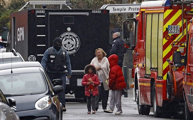 A woman and children are escorted by a police officer near a building where Mohammed Merah was holed up Thursday. (photo credit: AP/Remy de la Mauviniere)