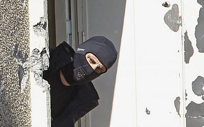 A masked police officer searches for clues at Mohamed Merah's apartment building in Toulouse in March. (Remy de la Mauviniere/AP)