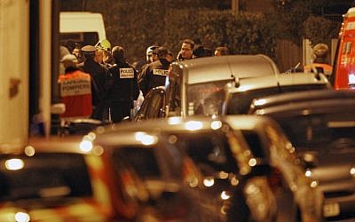 French police officers and firefighters stand next to the apartment building where Mohammed Merah was holed up late Wednesday. (photo credit: AP/Christophe Ena)