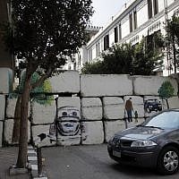 An Egyptian woman walks toward the painted concrete blocks wall that was part of the graffiti campaign in Cairo. ((photo credit: AP/Nasser Nasser)