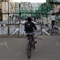 An Egyptian boy rides his bike next to an artist working on 'No Walls Street.' (photo credit: AP/Nasser Nasser)