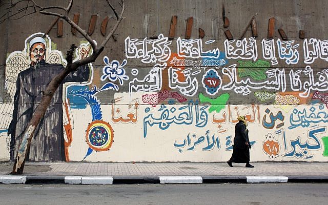 An Egyptian woman walks past a mural with a picture depicting a victim of clashes between protesters and army soldiers in December 2011, with verses of Quran that read in Arabic "God, we obeyed our lords and they misled us, punish them God twice as much and curse them" in Cairo, Egypt. (photo credit: AP Photo/Nasser Nasser) An Egyptian woman walks past a mural with a picture depicting a victim of clashes between protesters and army soldiers in December 2011, with verses of Quran that read in Arabic "God, we obeyed our lords and they misled us, punish them God twice as much and curse them" in Cairo, Egypt. (photo credit: AP Photo/Nasser Nasser)