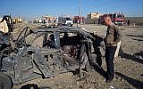 A man stands next to a bombed vehicle in Kirkuk, Iraq (photo credit: AP/Emad Matti)