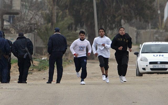 Palestinian boys jog past security officers during the Gaza Marathon. (photo credit: AP/Adel Hana)