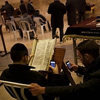 Two Jewish men check their smart phones as they read a religious scroll at the Western Wall, the holiest site where Jews pray, in Jerusalem's Old City. (photo credit: AP/Bernat Armangue)