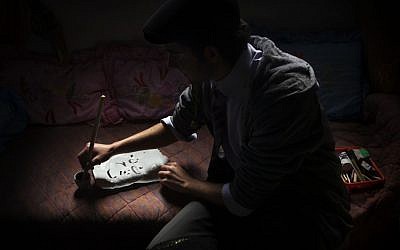 Palestinian calligraphy expert Qassem Sartawe, 22, prepares ink to be used for calligraphy works in the West Bank town of Bedya, near Nablus. (photo credit: AP/Bernat Armangue)