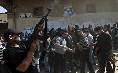 A Palestinian fires in the air during the funeral of Islamic Jihad terrorists in Gaza City (photo credit: AP/Adel Hana)