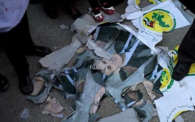 Protesters stand among damaged portraits of Hafez Al-Assad, former president of Syria. (photo credit: AP)