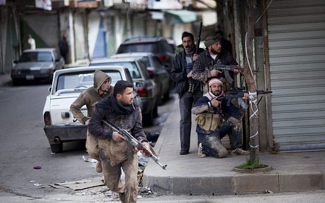 Syrian rebels take position during clashes with government forces in Idlib, near the Turkish border, Sunday (photo credit: Rodrigo Abd/AP)