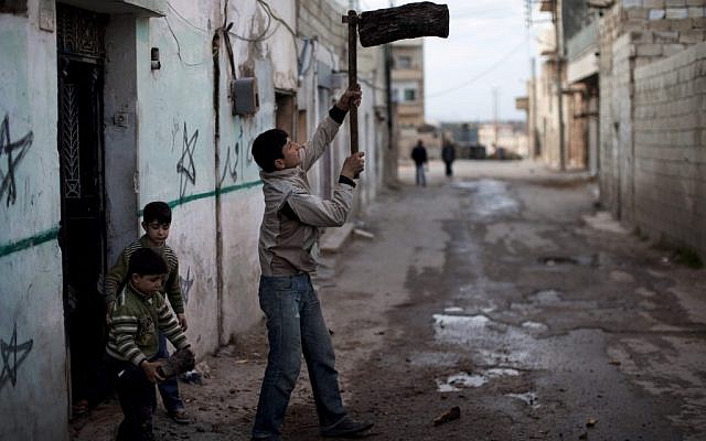 A boy chopping wood in Idlib, Syria (photo credit: AP/Rodrigo Abd)