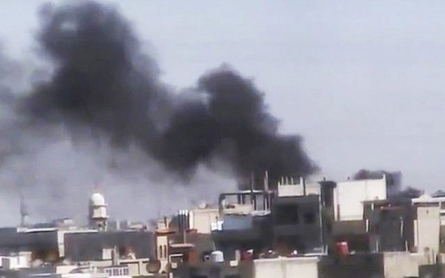 Smoke billows over Homs on Tuesday (photo credit: Syria Media Center/AP)
