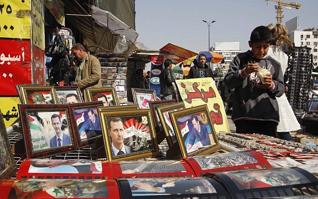 A street vendor displays pictures of Syrian President Bashar Assad in Damascus on Thursday. (photo credit: Muzaffar Salman/AP)