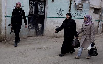 Syrian women walk by a member of the Free Syrian Army in Idlib on Monday (photo credit: Rodrigo Abd/AP)