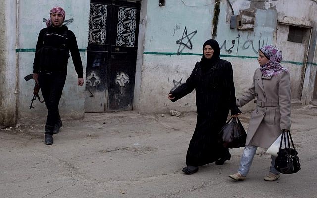 Syrian women walk by a member of the Free Syrian Army in Idlib on Monday (photo credit: Rodrigo Abd/AP) Syrian women walk by a member of the Free Syrian Army in Idlib on Monday (photo credit: Rodrigo Abd/AP)