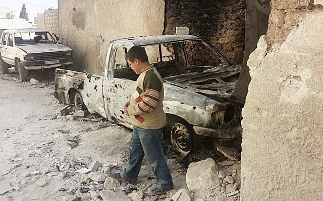 A boy examines cars damaged in an attack from Syrian government forces shelling at Sarmeen town in northern Syria. (photo credit: Edlib News Network/AP)