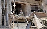 A man sits in his bombarded home in Homs April 22 (photo credit: AP)