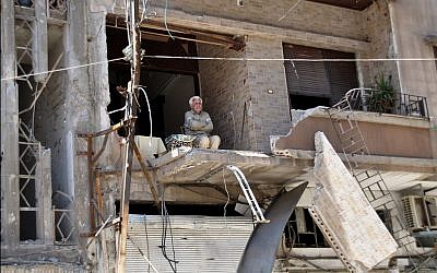 A man sits in his bombarded home in Homs April 22 (photo credit: AP)