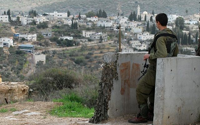An IDF soldier stands guard overlooking the Palestinian village of Qadum. (photo credit: Gili Yaari/Flash90) An IDF soldier stands guard overlooking the Palestinian village of Qadum. (photo credit: Gili Yaari/Flash90)