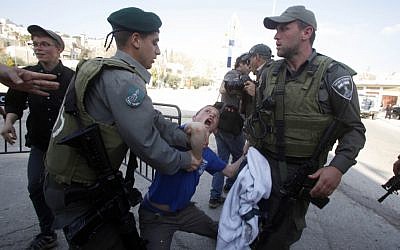 Border policemen scuffle with a boy outside the Beit Hamachpela building in Hebron on Wednesday. (photo credit: Uri Lenz/Flash 90)