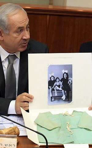 Prime Minister Benjamin Netanyahu presents the shirt of a child who was murdered during the Holocaust, at a cabinet meeting on Tuesday (photo credit: Haim Zach/Pool/Flash90)