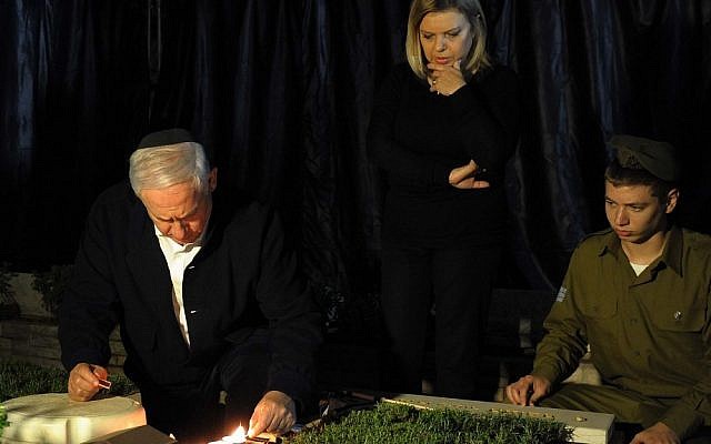 Prime Minister Benjamin Netanyahu sits next to the grave of his late brother, Yonatan, at the military cemetery on Mount Herzl in Jerusalem on Sunday (photo credit: Avi Ohayon/Pool/Flash 90)