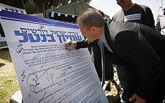 Environmental Protection Minister Gilad Erdan signs a petition calling for a universal service law to replace the Tal Law, at the Suckers' Tent in Jerusalem on Sunday. (photo credit: Miriam Alster/Flash90)