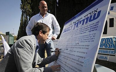 MK Yitzhak Herzog at the 'Suckers' Tent' signing the petition calling for universal service law to replace the Tal Law. April 23 2012. (photo credit: Miriam Alster/Flash90)