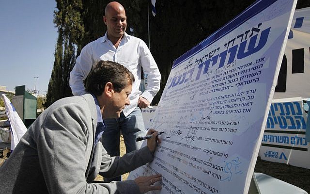 MK Yitzhak Herzog at the 'Suckers' Tent' signing the petition calling for universal service law to replace the Tal Law. April 23 2012. (photo credit: Miriam Alster/Flash90)