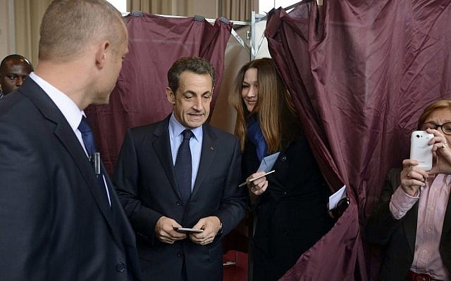 French President and UMP candidate Nicolas Sarkozy and his wife Carla Bruni-Sarkozy exit the voting booth as they prepare to cast their votes in the first round of French presidential elections in Paris, Sunday  (photo credit: AP Photo/Eric Feferberg)